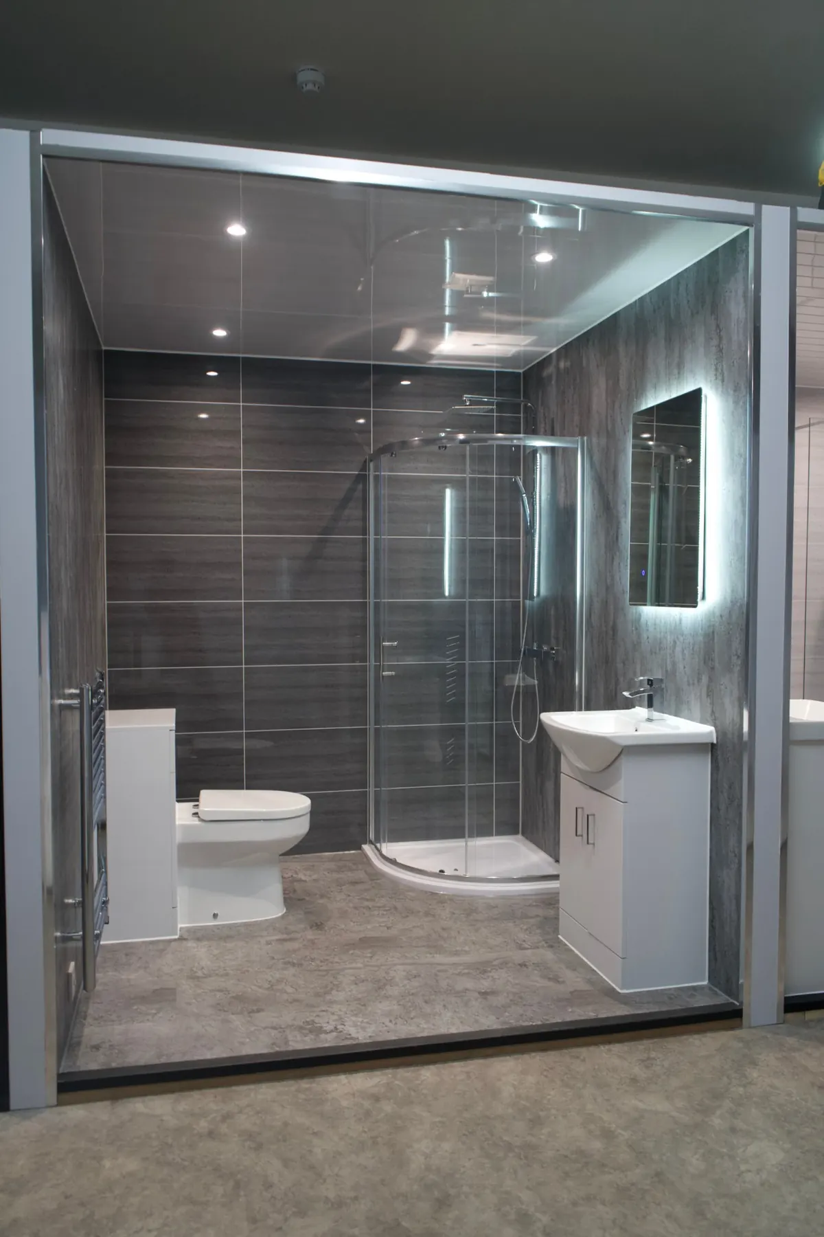 Showroom bathroom with grey panels, quadrant shower enclosure and white vanity unit