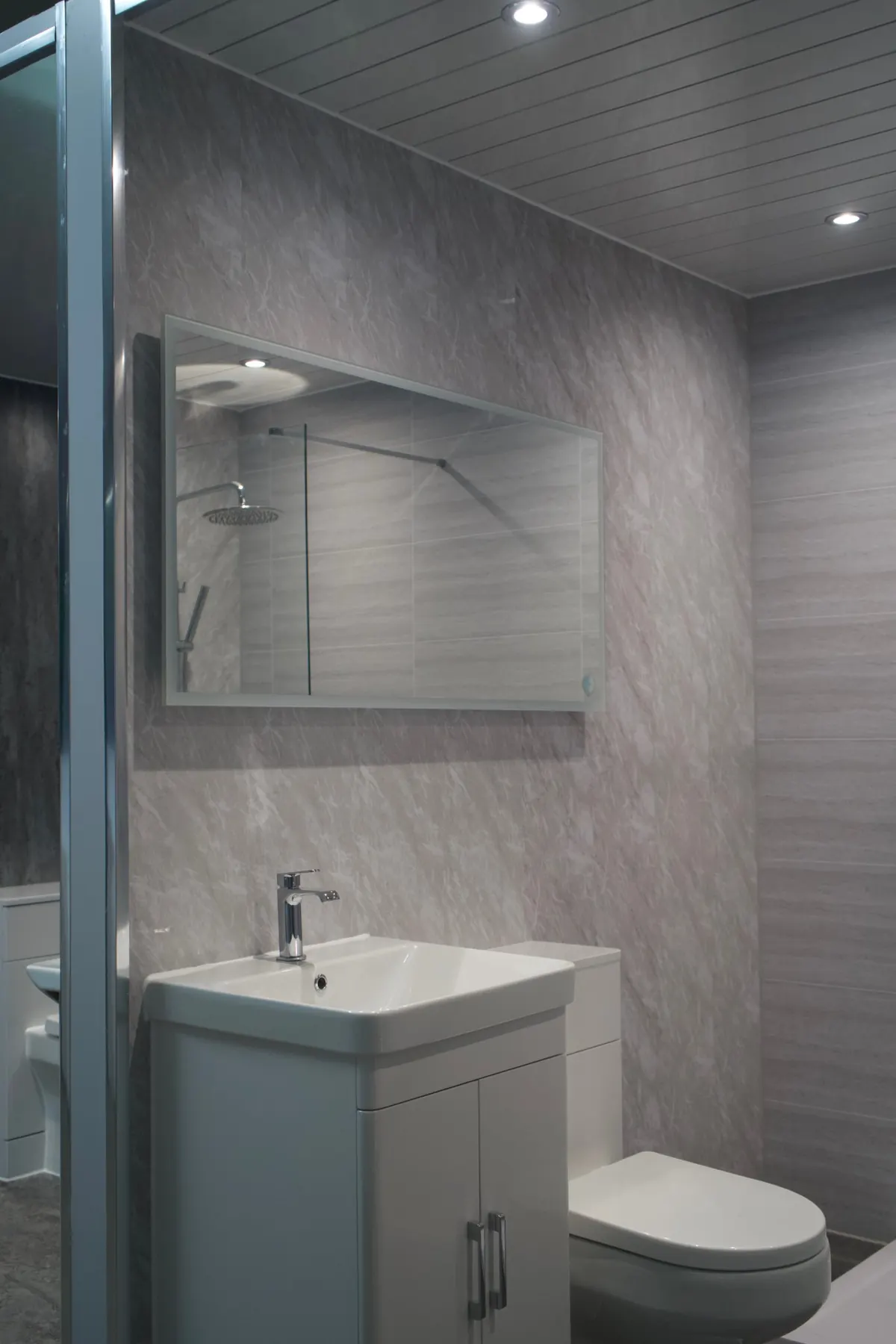 White vanity basin and back-to-wall toilet with grey stone-effect panels